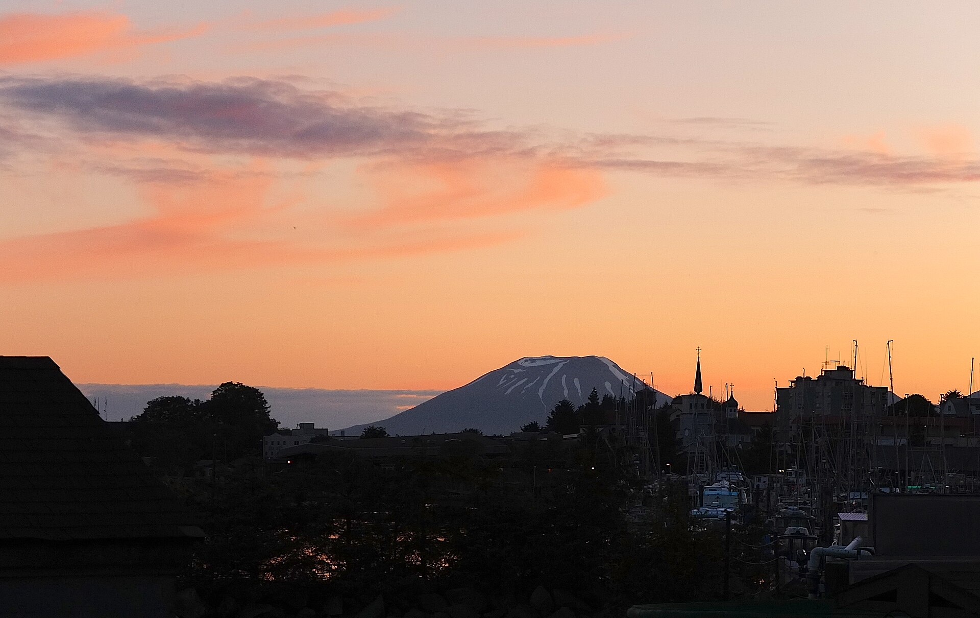 Mount Edgecumbe at sunset beyond the masts of Sitka's harbour