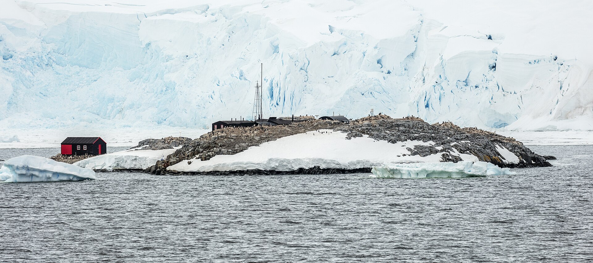 Port Lockroy's Base A on Goudier Island beneath glacier walls