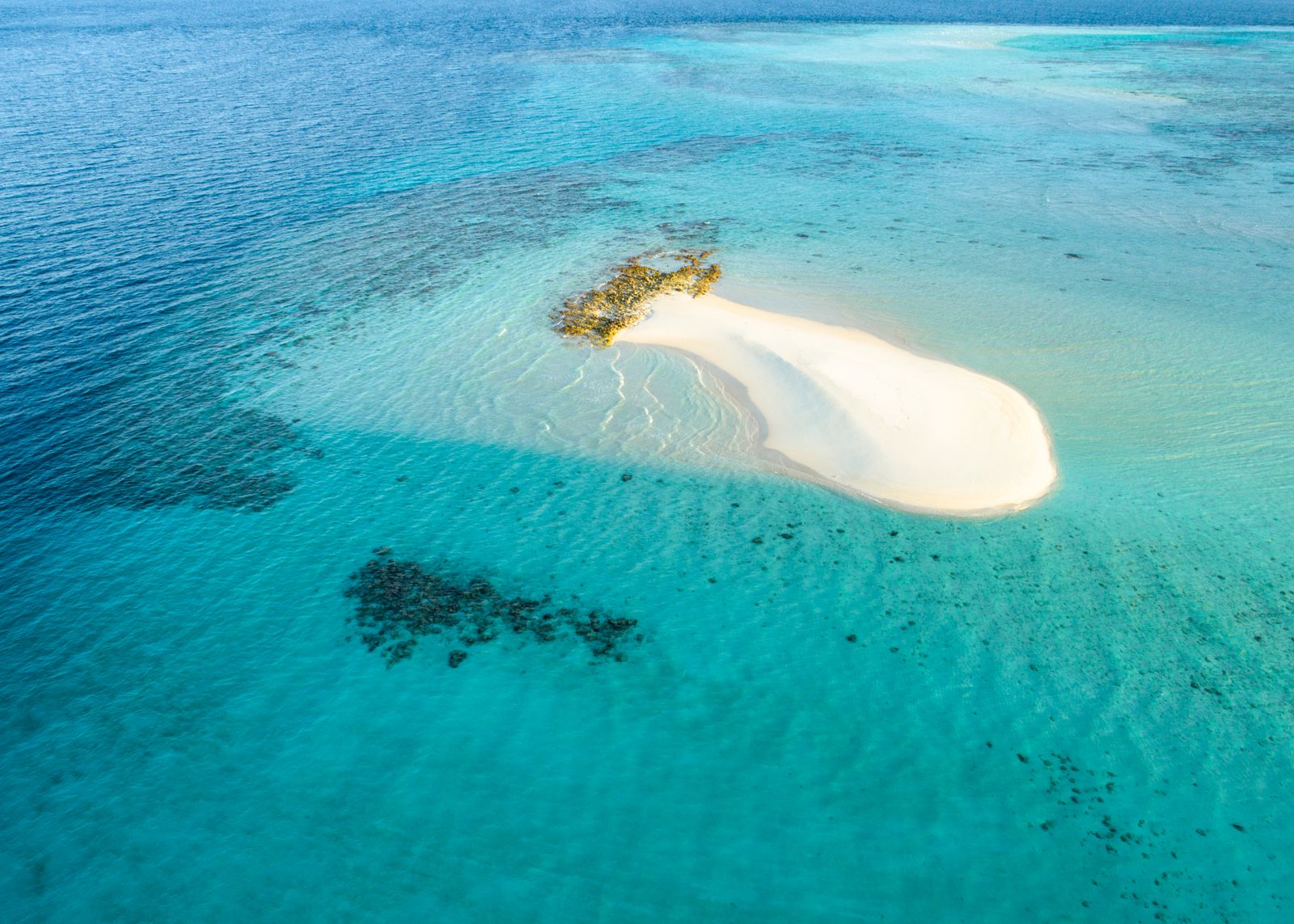 Aerial view of a sandy island ringed by turquoise water