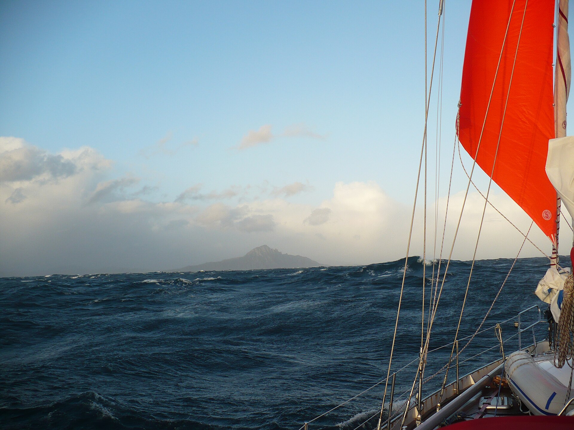 Cape Horn sighted from the deck of a yacht under orange storm sail