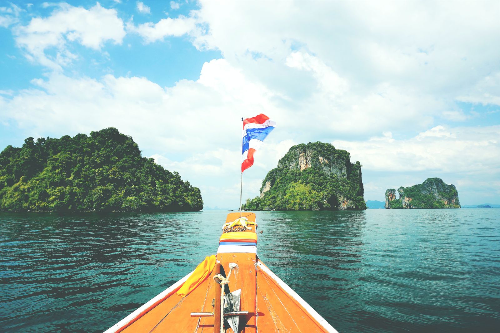 A long-tail boat crossing calm water toward the islands of the Andaman Sea